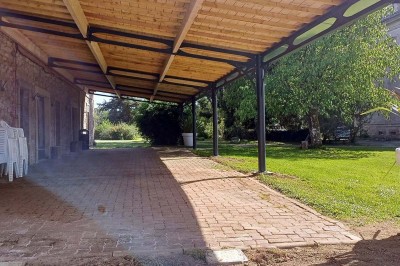 Pelouse verdoyante entourée de grands arbres sous un ciel partiellement nuageux.