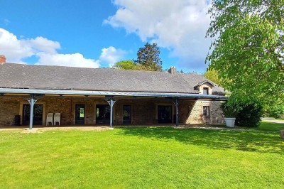 Pelouse verdoyante entourée de grands arbres sous un ciel partiellement nuageux.