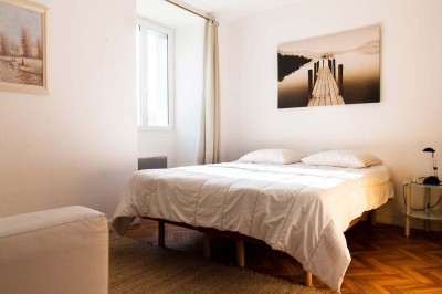 Pelouse verdoyante entourée de grands arbres sous un ciel partiellement nuageux.