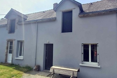 Pelouse verdoyante entourée de grands arbres sous un ciel partiellement nuageux.