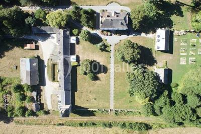 Étang calme entouré d'arbres avec un bâtiment blanc visible en arrière-plan sous un ciel bleu.