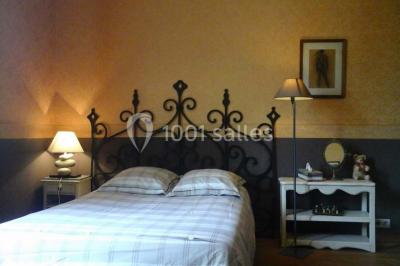 Étang calme entouré d'arbres avec un bâtiment blanc visible en arrière-plan sous un ciel bleu.