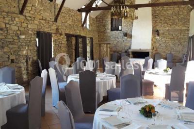 Étang calme entouré d'arbres avec un bâtiment blanc visible en arrière-plan sous un ciel bleu.