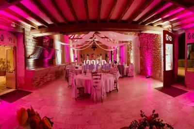 Salle de réception décorée avec des tables dressées, éclairage rose et éléments suspendus en tissu.