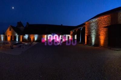 Cour intérieure en soirée avec des bâtiments en pierre éclairés par des lumières orange et un ciel nocturne en arrière-plan.
