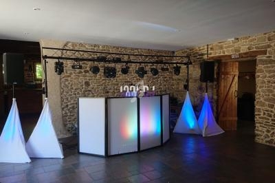 Installation de matériel de sonorisation et d'éclairage avec une structure lumineuse dans une salle en pierre.