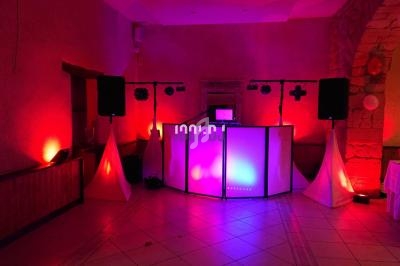 Installation de matériel de sonorisation et éclairage coloré dans une salle de réception avec murs en pierre.