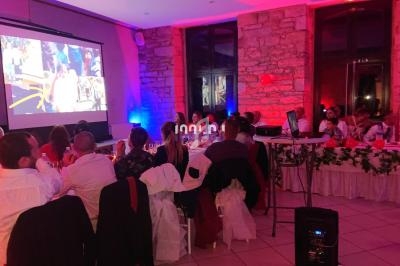 Des invités assis regardent une projection dans une salle décorée avec des lumières colorées et des murs en pierre.