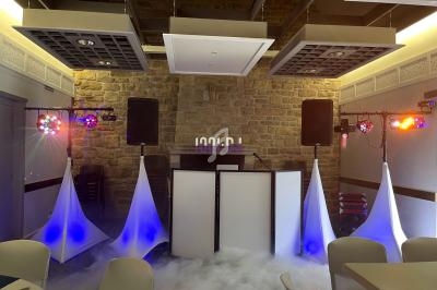 Installation de matériel de sonorisation et éclairage avec effets de fumée dans une salle en pierre.