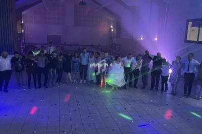 Groupe de personnes dansant en cercle sur une piste éclairée par des lumières colorées dans une salle sombre.