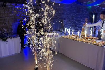 Fontaines lumineuses allumées devant une table de buffet décorée, dans une salle en pierre avec éclairage bleu.