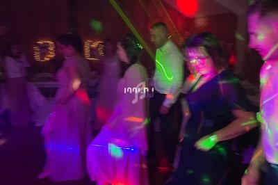 Des personnes dansent sous des lumières colorées dans une ambiance festive en intérieur.