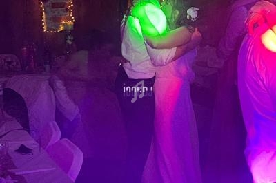 Un couple danse tendrement sous des lumières colorées dans une ambiance festive et tamisée.