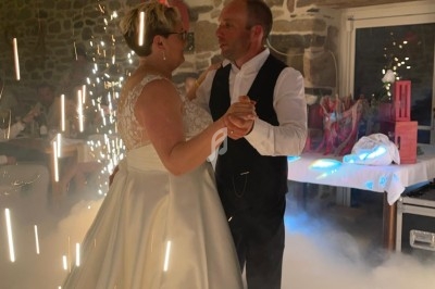 Un couple danse dans une salle en pierre illuminée, entouré d'effets de lumière et de fumée.