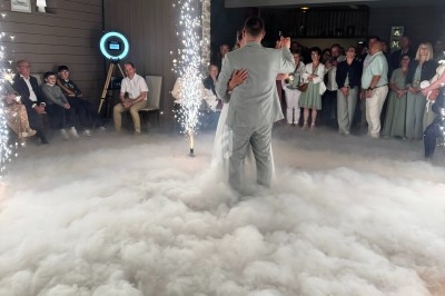Un couple danse au milieu d'une piste entourée de fumée et d'étincelles, sous le regard des invités.