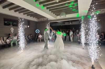Un couple danse au milieu d'une piste enveloppée de fumée, entourée de jets d'étincelles et d'invités.