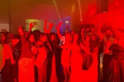 Groupe de personnes dansant et posant sous un éclairage rouge dans une salle avec murs en pierre.