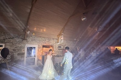 Un couple danse sous des jeux de lumière et de fumée dans une salle en pierre avec un plafond en bois.
