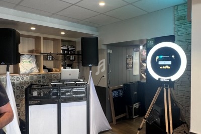 Poste de DJ avec platines, enceintes et éclairage, accompagné d'un photobooth avec anneau lumineux dans un espace intérieur.