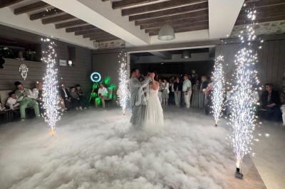 Un couple danse au milieu d'une piste recouverte de fumée, entourée de fontaines d'étincelles, sous un plafond en poutres…