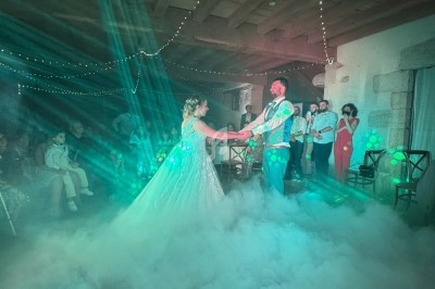 Un couple danse sous des lumières colorées et un effet de fumée dans une salle décorée de guirlandes lumineuses.