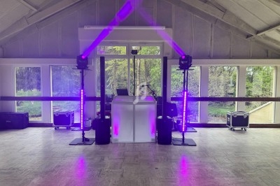 Installation de matériel de sonorisation et éclairage violet dans une salle avec de grandes fenêtres donnant sur un espace…