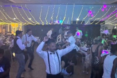 Des personnes dansent sous des guirlandes lumineuses dans une salle décorée pour une fête.