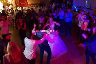 Des invités dansent autour d'un couple de mariés sur une piste éclairée lors d'une réception festive.