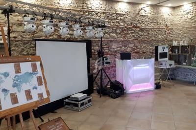 Salle décorée pour un événement avec éclairage, cabine DJ lumineuse, carte du monde et accessoires festifs.