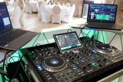 Équipement de DJ comprenant une table de mixage et deux ordinateurs portables dans une salle de réception.