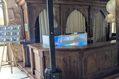 Système de sonorisation compact installé devant un comptoir en bois dans une salle avec murs en pierre apparente.