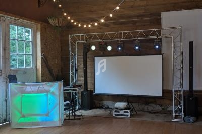Installation de matériel audiovisuel dans une salle en bois, avec projecteur, éclairages et console lumineuse.