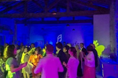 Des personnes dansent sous des lumières colorées dans une salle avec une charpente en bois visible au plafond.