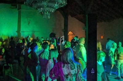 Groupe de personnes dans une salle éclairée par des lumières colorées, avec un grand lustre au plafond.