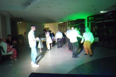 Des personnes dansent et discutent dans une salle éclairée par des lumières colorées, ambiance festive.