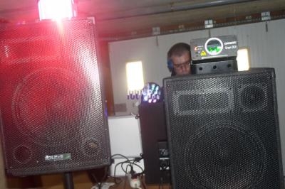 Deux enceintes noires en gros plan avec un homme en arrière-plan utilisant du matériel audio dans une pièce.