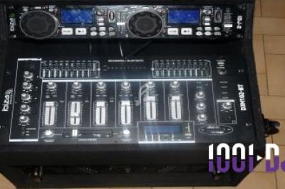 Console de mixage DJ avec platines et commandes sur un support noir, posée sur un sol carrelé beige.