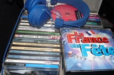 Casque audio bleu posé sur une collection de CD musicaux variés, dont un intitulé ’La France en fête’.