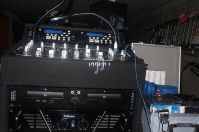 Table de mixage et amplificateur audio installés dans un rack, entourés de câbles et d'équipements de sonorisation.