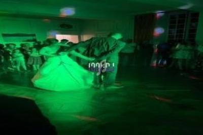 Un couple danse sous des lumières vertes dans une salle entourée de spectateurs.