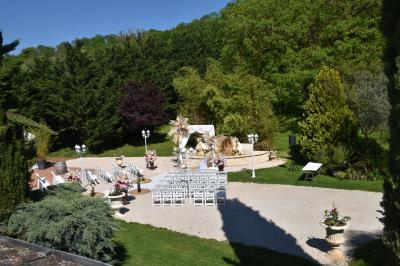 Allée bordée de pelouse et d'arbres taillés, sous un ciel dégagé dans un jardin verdoyant.