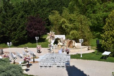 Allée bordée de pelouse et d'arbres taillés, sous un ciel dégagé dans un jardin verdoyant.