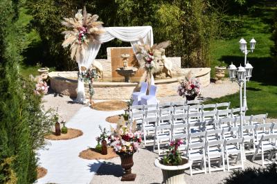 Allée bordée de pelouse et d'arbres taillés, sous un ciel dégagé dans un jardin verdoyant.