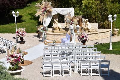 Allée bordée de pelouse et d'arbres taillés, sous un ciel dégagé dans un jardin verdoyant.