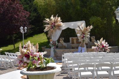 Allée bordée de pelouse et d'arbres taillés, sous un ciel dégagé dans un jardin verdoyant.
