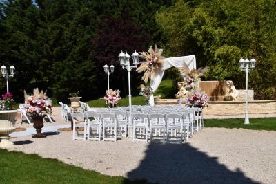 Allée bordée de pelouse et d'arbres taillés, sous un ciel dégagé dans un jardin verdoyant.