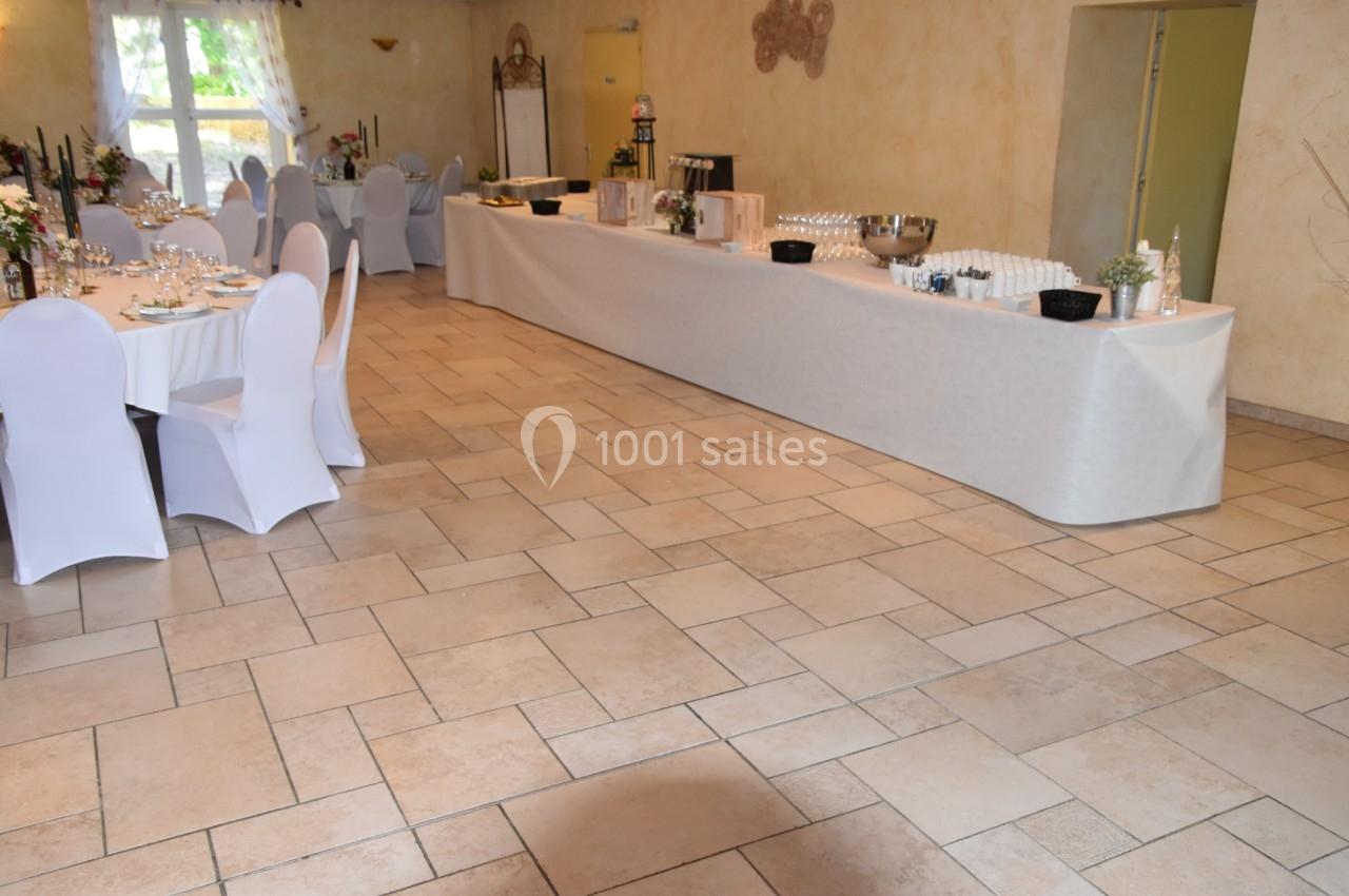 Salle de réception avec tables dressées et un buffet aligné sur une longue table blanche.