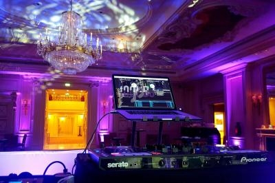 Table de mixage avec ordinateur portable dans une salle de réception éclairée par des lumières colorées et un lustre.