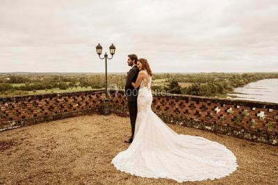 Lever de soleil illuminant un jardin avec des arbres, un muret en pierre et une vue sur un paysage brumeux.