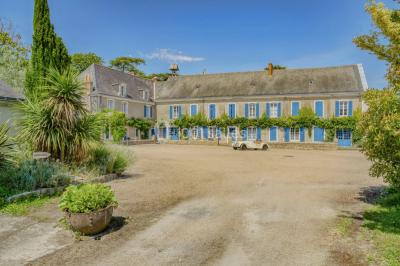Lever de soleil illuminant un jardin avec des arbres, un muret en pierre et une vue sur un paysage brumeux.